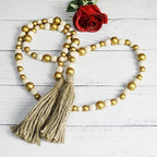 CVHOMEDECO. Wood Beads Garland with Tassels Farmhouse Rustic Wooden Prayer Bead String Wall Hanging Accent for Home Festival Decor. Gold Mix